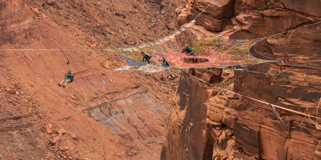 BASE jumpers prepare to jump from the Mothership Spacenet suspended from the cliffs 950 vertical feet above the valley floor at Mineral Canyon in Moab, Utah.
