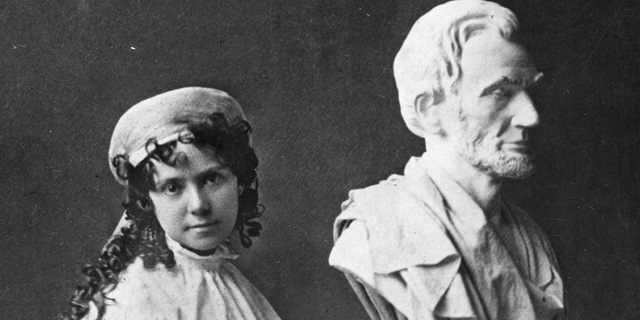 American sculptor Vinnie Ream (1847-1914) poses beside her bust of Abraham Lincoln. Created when she was only a teenager, she was both the first woman and the youngest artist to be commissioned by the U.S. government for a statue.
