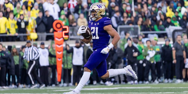Running back Wayne Taulapapa #21 of the Washington Huskies runs fro a touchdown against the Oregon Ducks during the first half of the game at Autzen Stadium on November 12, 2022 in Eugene, Oregon.