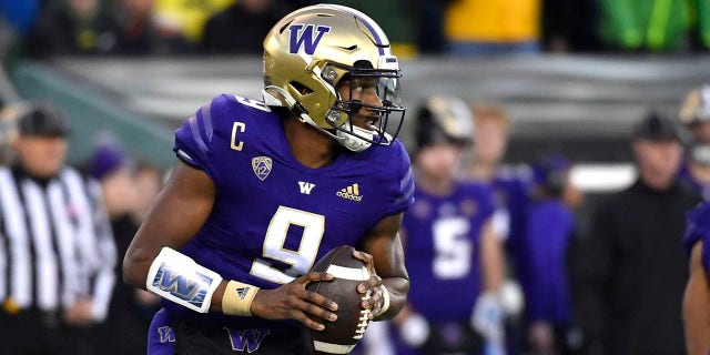 Washington quarterback Michael Penix Jr. (9) rolls away from Oregon defenders and looks for a receiver during the first half of an NCAA college football game Saturday, Nov. 12, 2022, in Eugene, Ore.