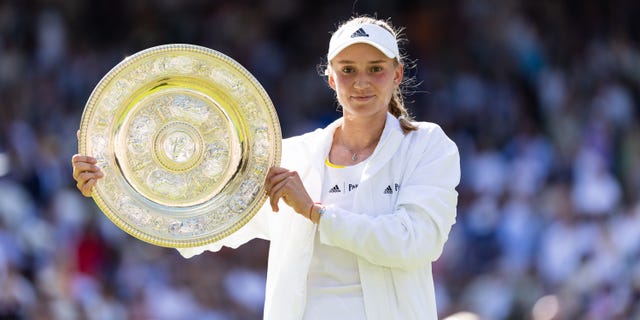 Elena Rybakina of Kazakhstan holds the winner's trophy after defeating Ons Jabeur of Tunisia in the women's singles final of the Wimbledon Championships at The All England Club in Wimbledon, London, on July 9, 2022.