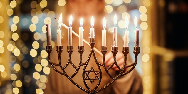 A child lighting the Menorah candles for Hanukkah celebration over the holiday.