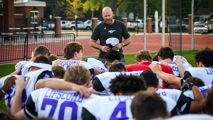 Former Super Bowl winning quarterback and ESPN NFL analyst Trent Dilfer says a prayer with his team before the start of practice as the new head coach of Lipscomb Academy