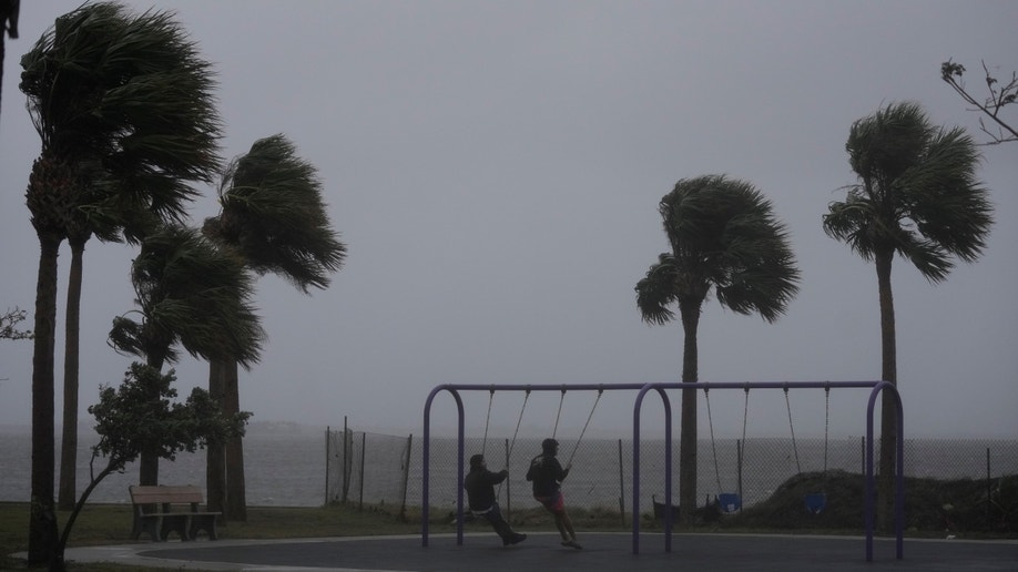 People on swingset before Hurricane Nicole landfall