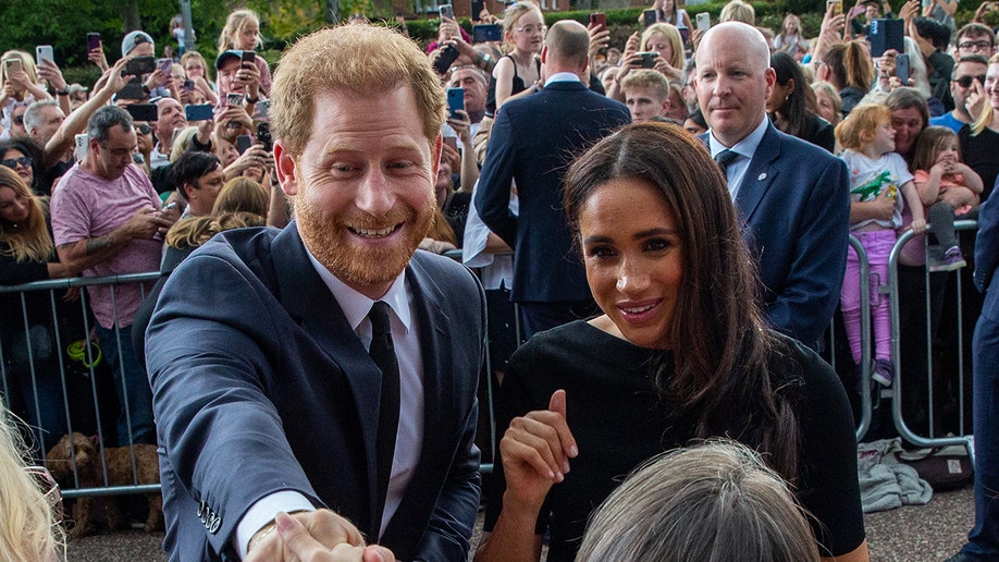 Prince Harry and Meghan Markle greet a large group of fans outside Windsor Castle after the death of the Queen