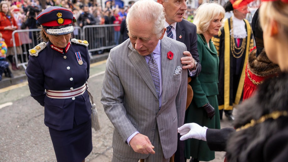 King Charles looks down in shock at the ground where there are broken eggs