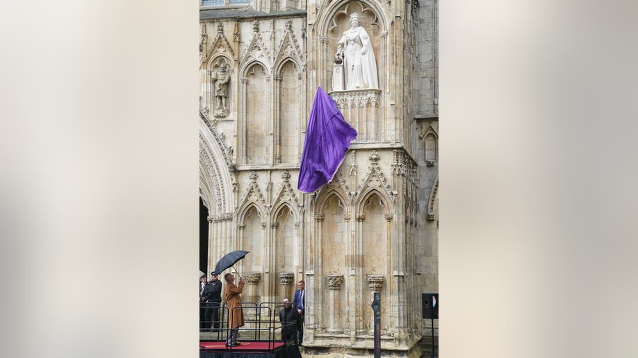 Dramatic dropping of purple curtain unveiling Queen Elizabeth II statue