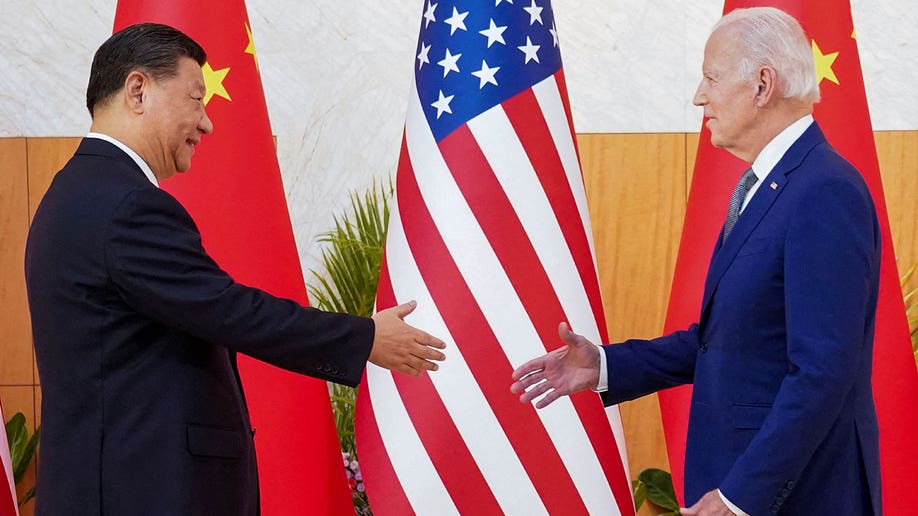 Biden and Xi shake hands in front of the Chinese and US flags