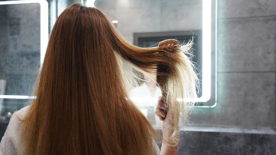 Mujer cepilla el pelo liso