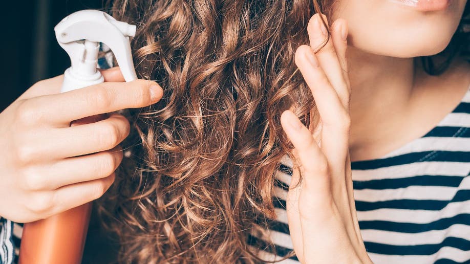 Woman styles wavy hair with spray bottle