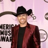 Country star Dustin Lynch sports a crimson colored suit with black shirt and hat