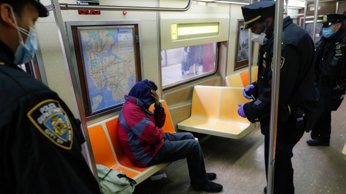 New York Police Department officers wake up sleeping subway passengers