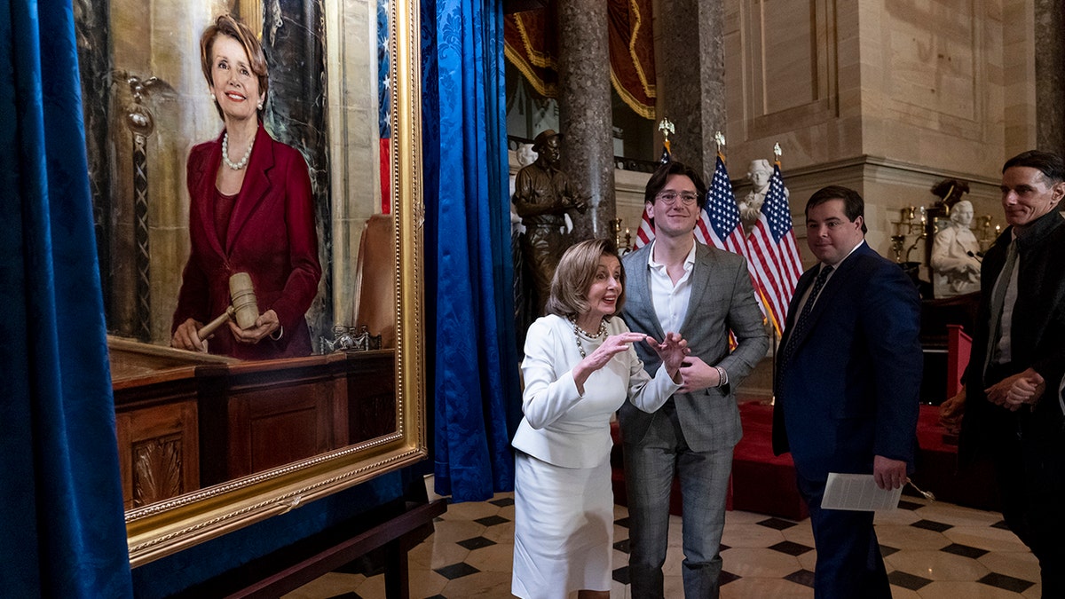 Nancy Pelosi standing next to her portrait