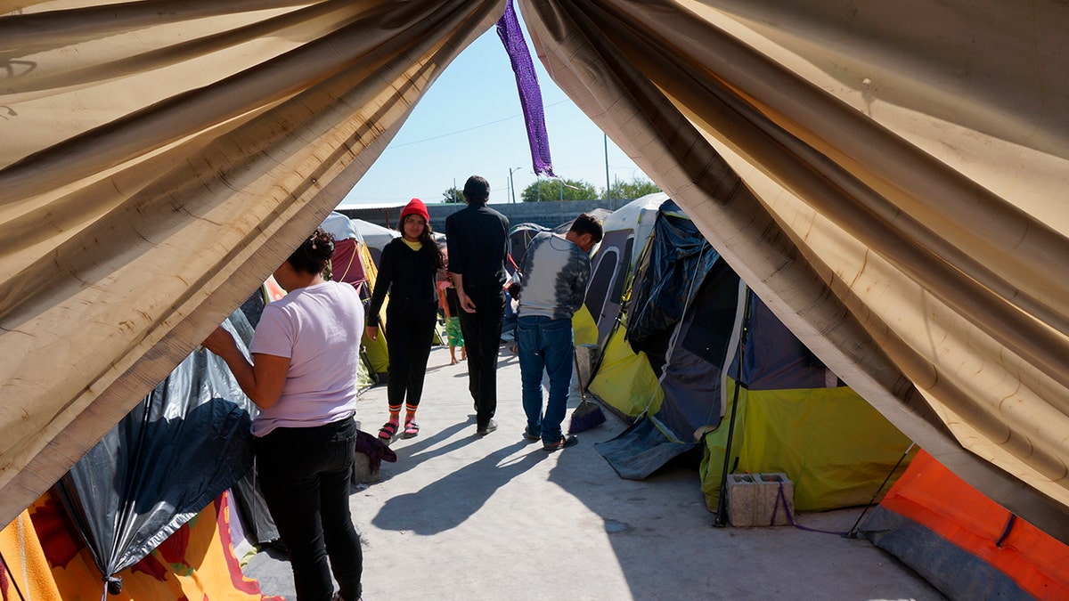 Migrants standing outside of a tent