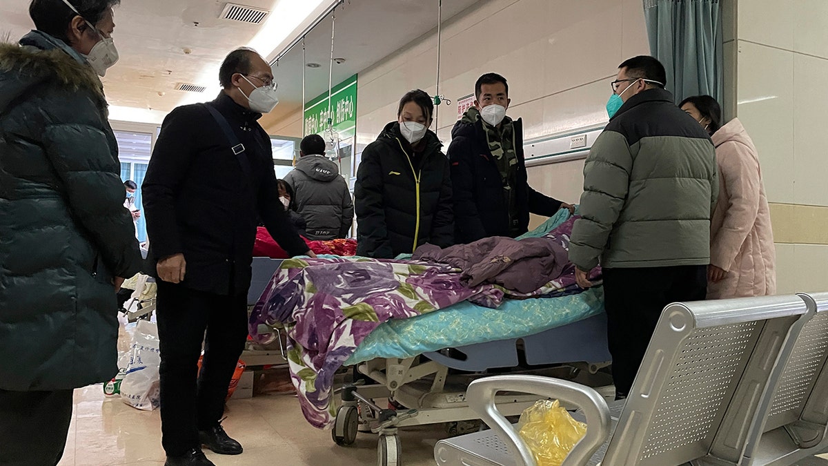 People standing around a hospital bed