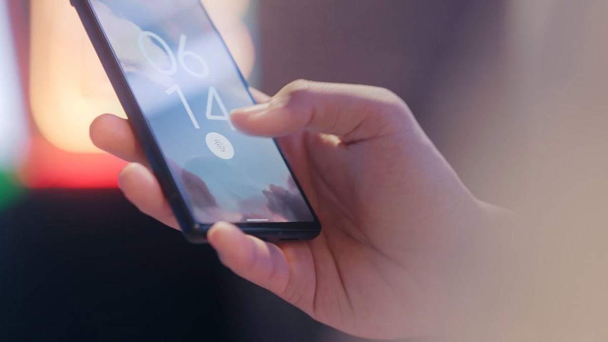 Someone holds their iPhone showing the thumbprint image