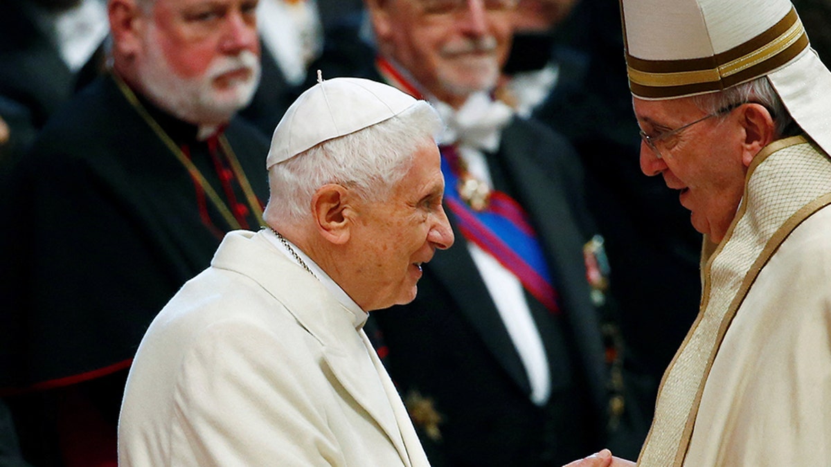 Pope Francis shakes hands with Pope Emeritus Benedict XVI in 2015