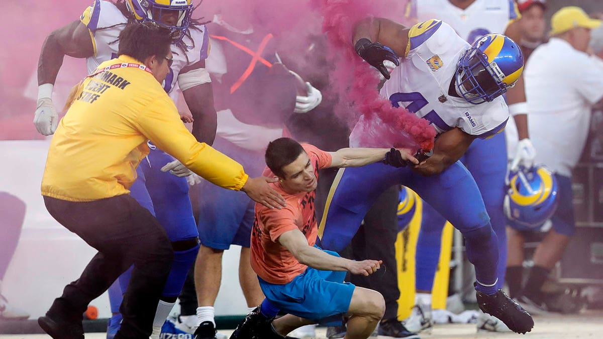 Rams players tackle a prostester