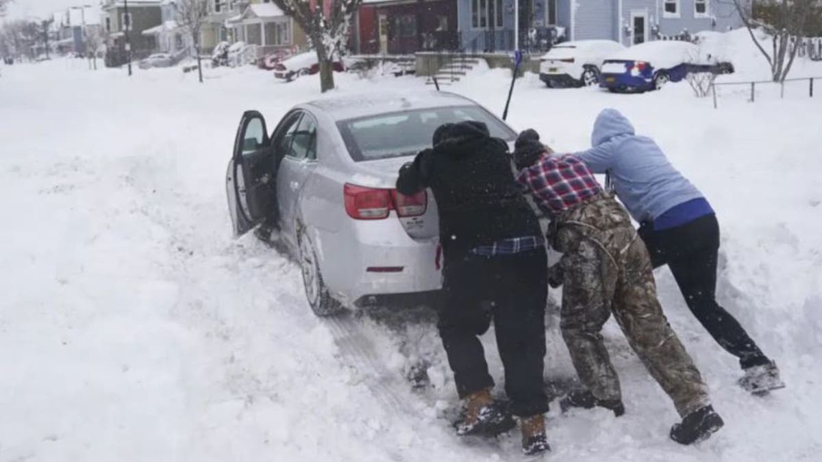 Neighbors help push motorist stuck snow
