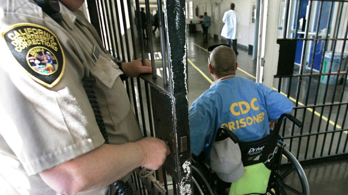 FILE - A wheelchair-bound inmate wheels himself through a checkpoint at the California Medical Facility in Vacaville, Calif., on April 9, 2008. A prominent California medical school has apologized for conducting unethical experimental medical treatments on 2,600 incarcerated men in the 1960s and 1970s. (AP Photo/Rich Pedroncelli, File) 