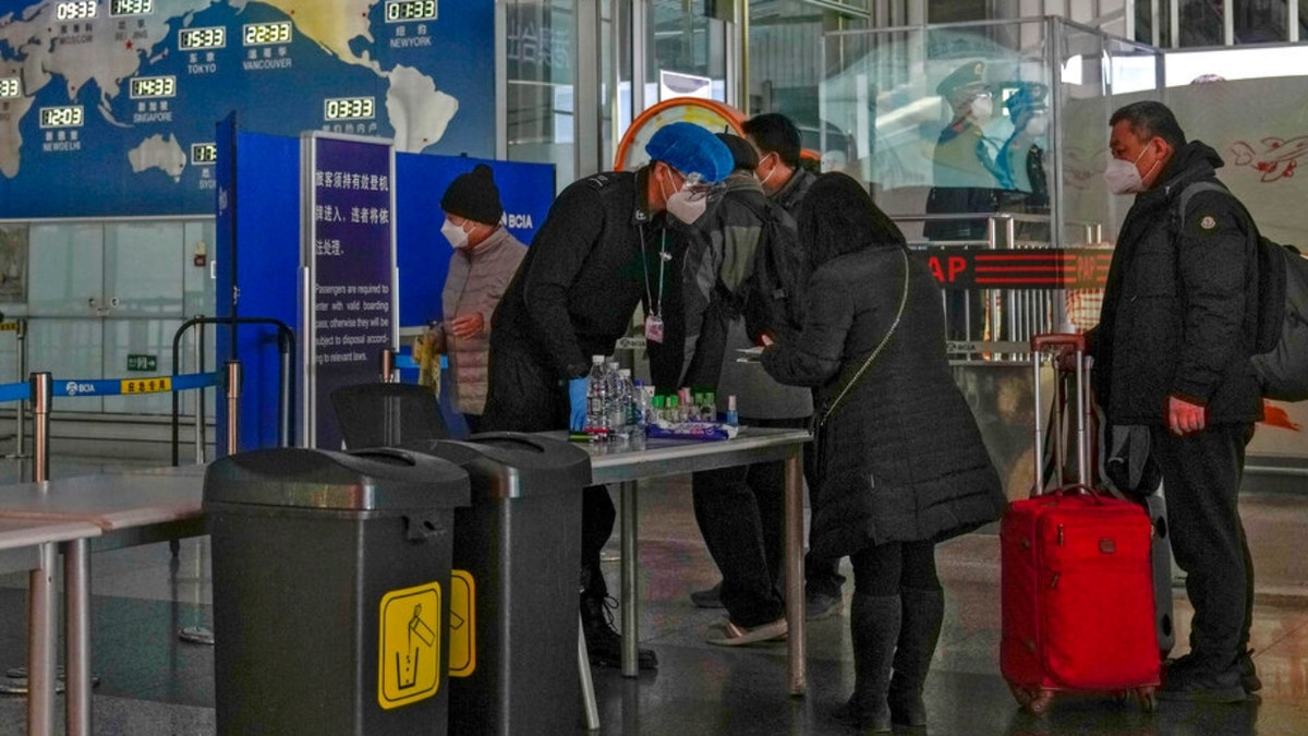 Passengers wearing face masks line up for security check