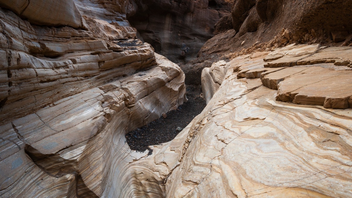 An asphalt trail leads through the smooth white polished marble walls in Death Valley National Park's Mosaic Canyon