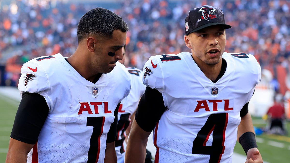 Falcons quarterbacks Marcus Mariota and Desmond Ridder walk off the field