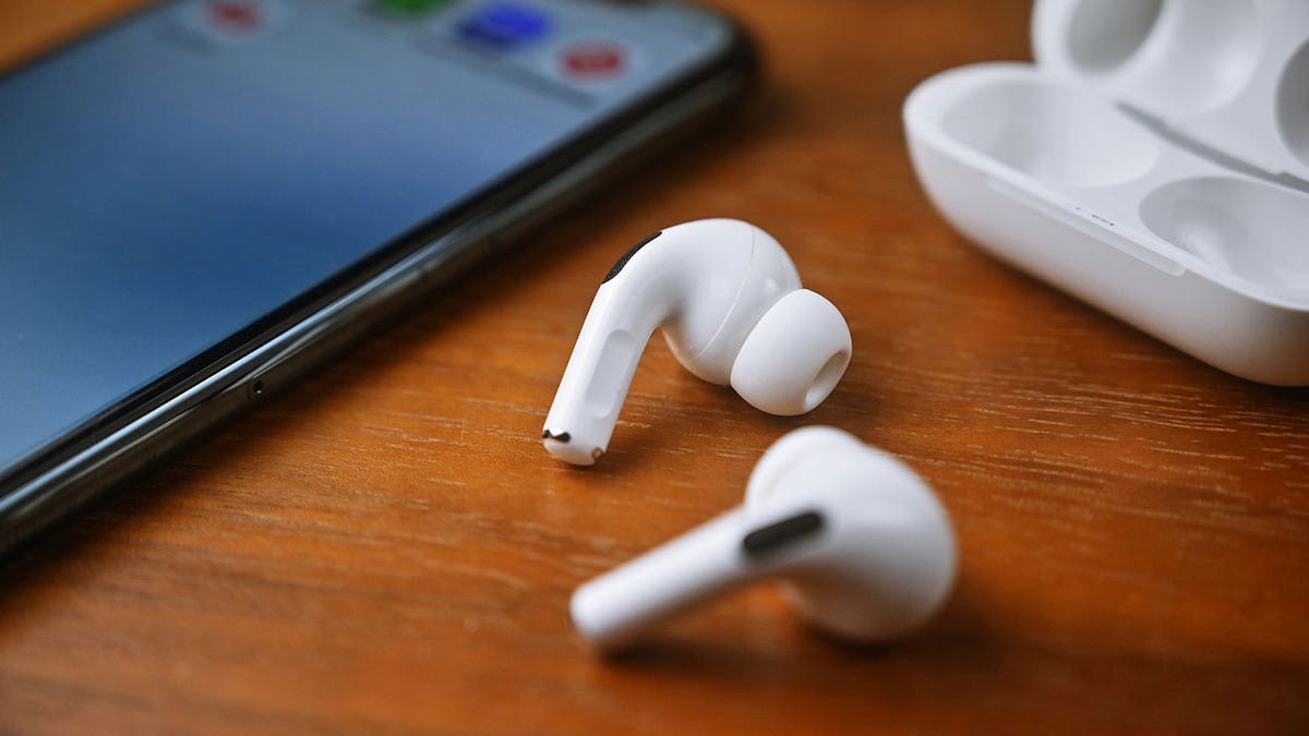 White earbuds resting on a wooden table.