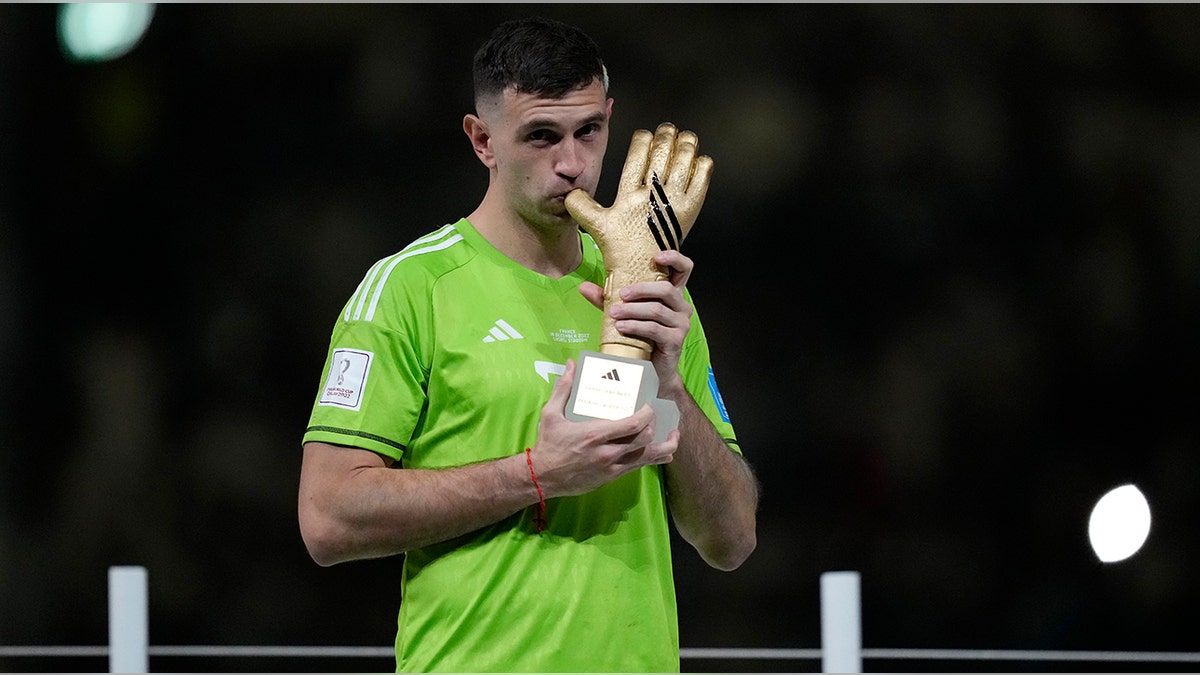 Emiliano Martinez kisses the glove trophy