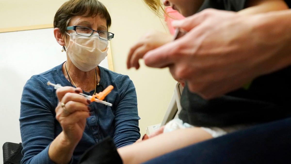 Deborah Sampson, left, a nurse at a University of Washington Medical Center clinic in Seattle, gives a Pfizer COVID-19 vaccine shot to a 20-month-old child, June 21, 2022, in Seattle.