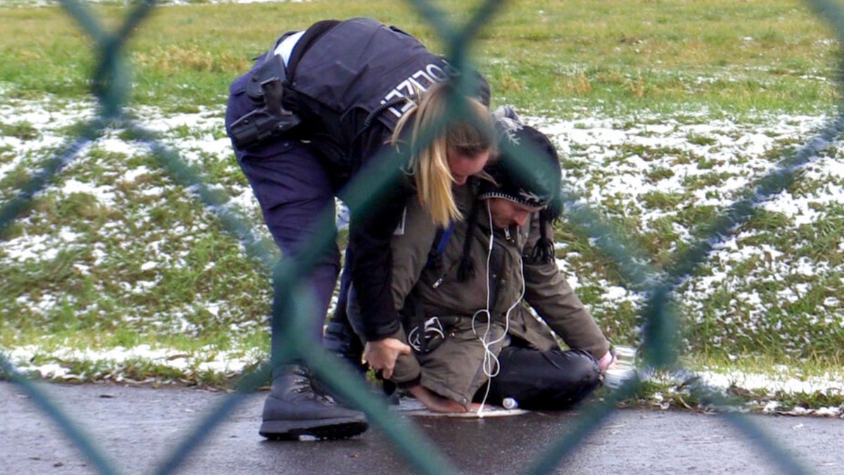 A police officer attempts to remove a protester from a street at the Berlin Airport