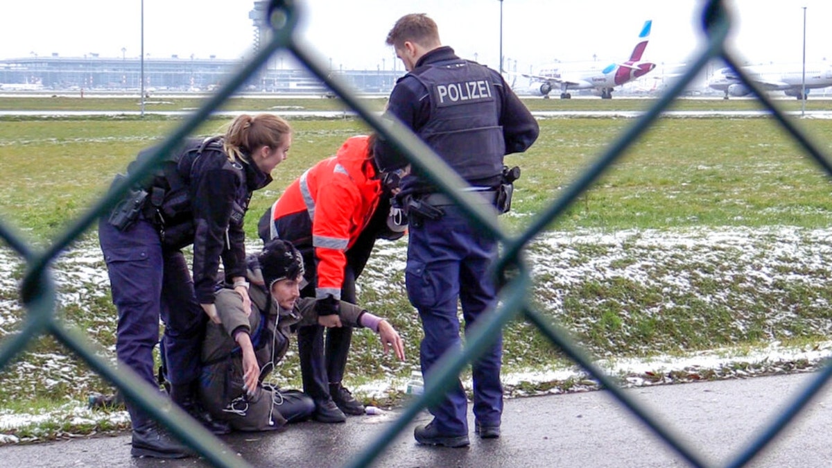 A police officer tries to remove an activist from the ground at the Berlin Airport