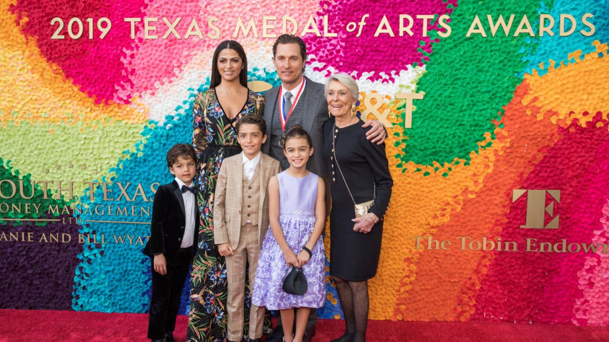 Matthew McConaughey poses with his family Camila in a long dress, his mother Kay and three children on the red carpet