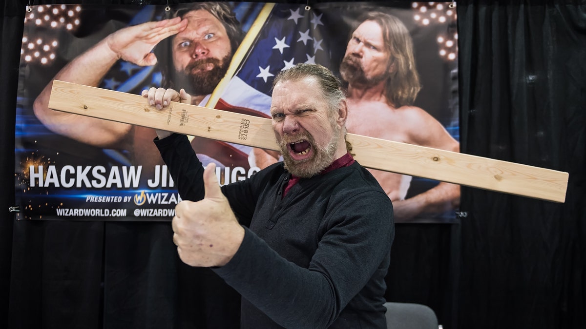 Jim Duggan posing with 2x4 and old wrestling photos