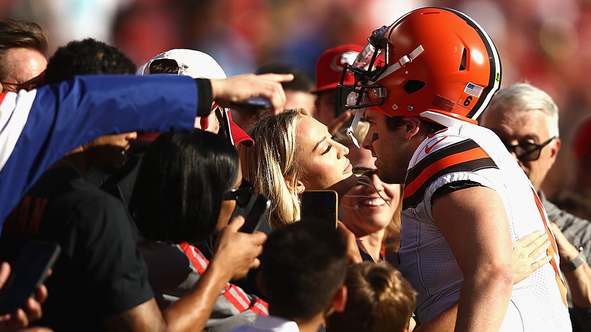 Baker Mayfield embraces his wife on the sidelines before an NFL game