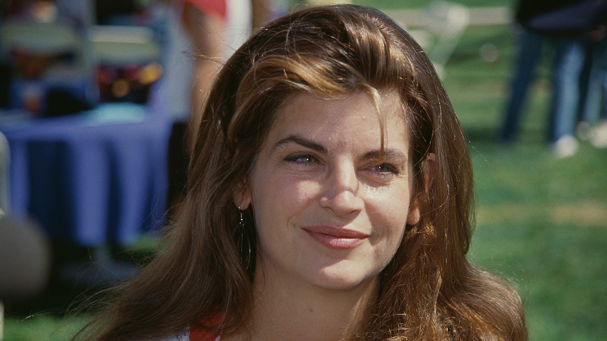Kirstie Alley smiles looking off away from the camera with one little strand of hair falling in her face