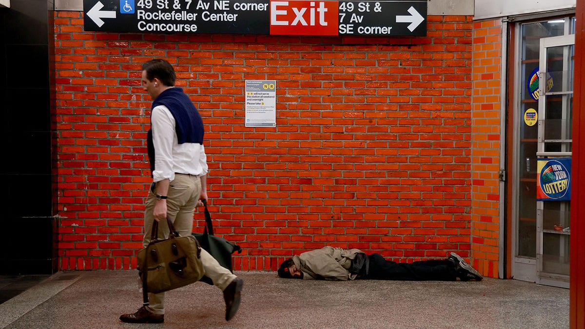 business man walks past homeless