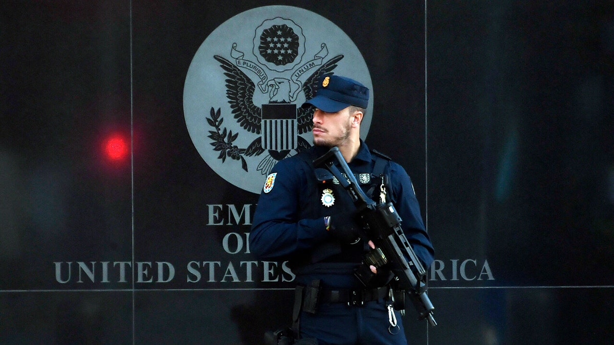 A guard with a gun in front of the embassy
