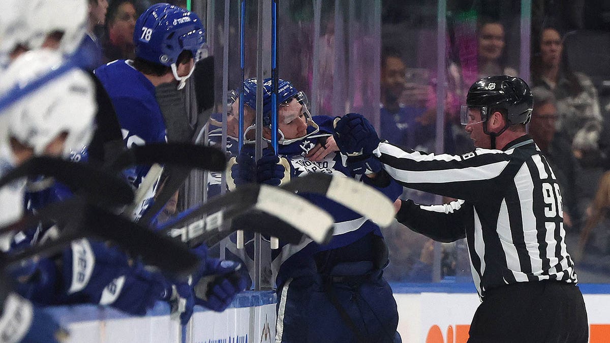 Linesman Dan Kelly shoves Leafs winger Michael Bunting off the ice after a fight