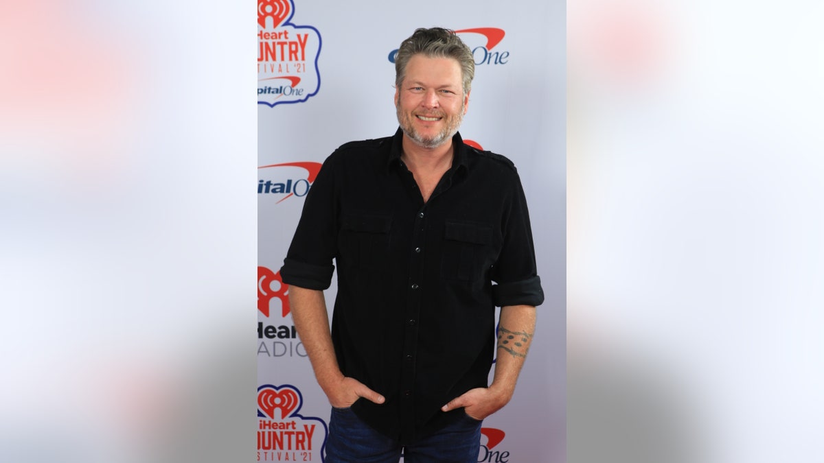 Blake Shelton puts his hands in his pockets on the red carpet while wearing a black shirt