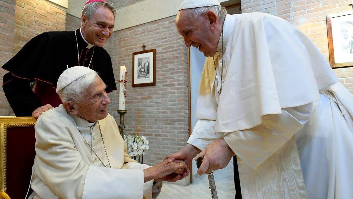 Pope Francis shakes hands with Pope Emeritus Benedict XVI