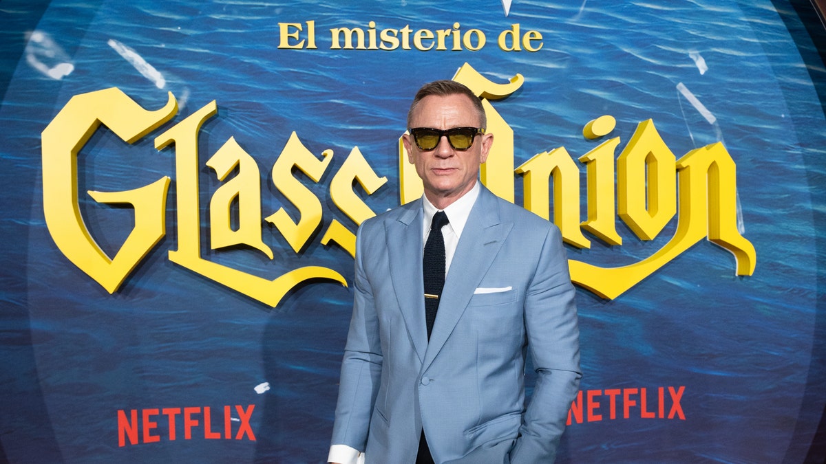 Daniel Craig on the red carpet for "Glass Onion: A Knives Out Mystery" in black sunglasses and a light blue suit with a black tie
