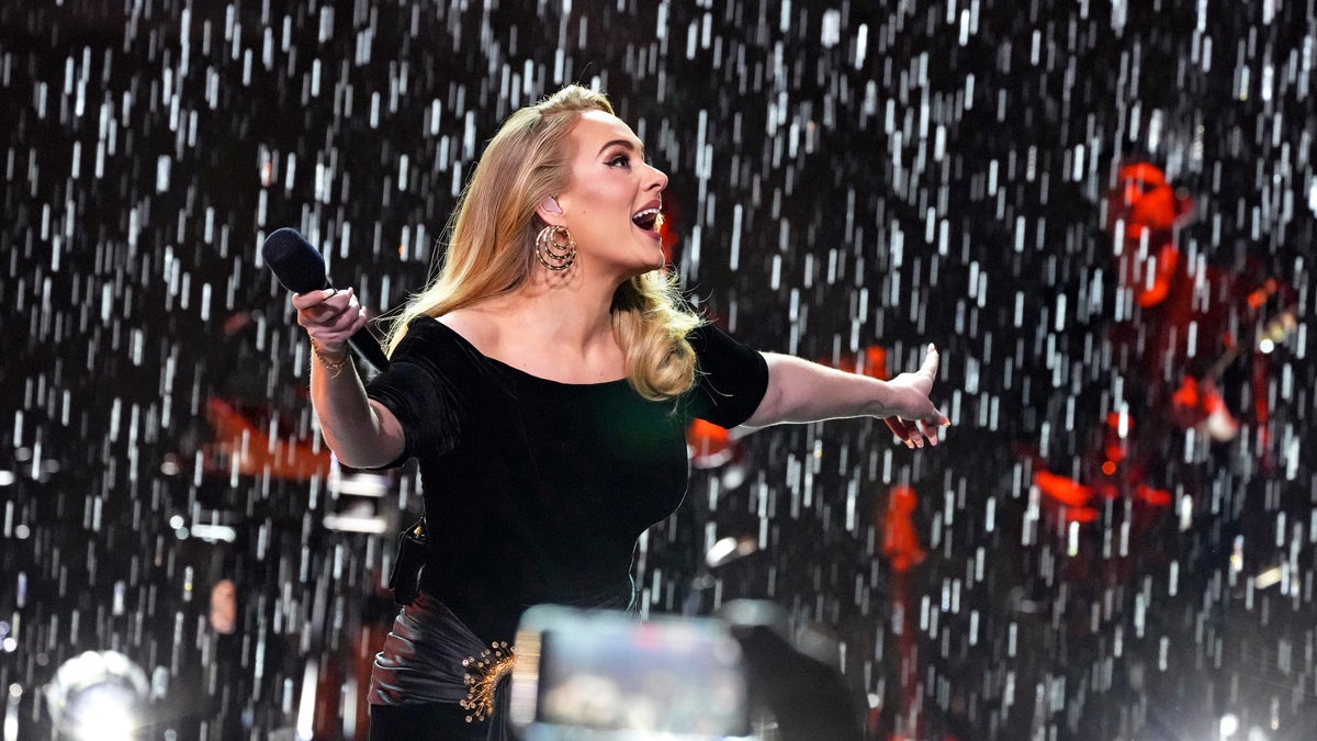 Adele performing on stage as rain falls down