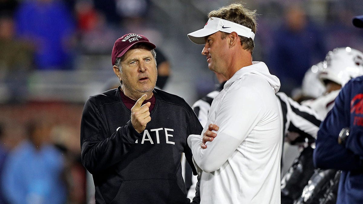 Mike Leach and Lane Kiffin talk on the field