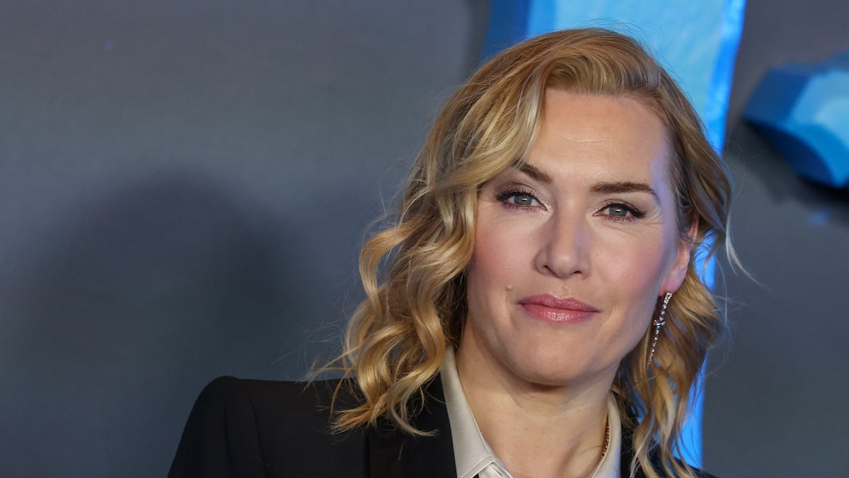 Kate Winslet with ringlet curls in a black suit and white top on red carpet
