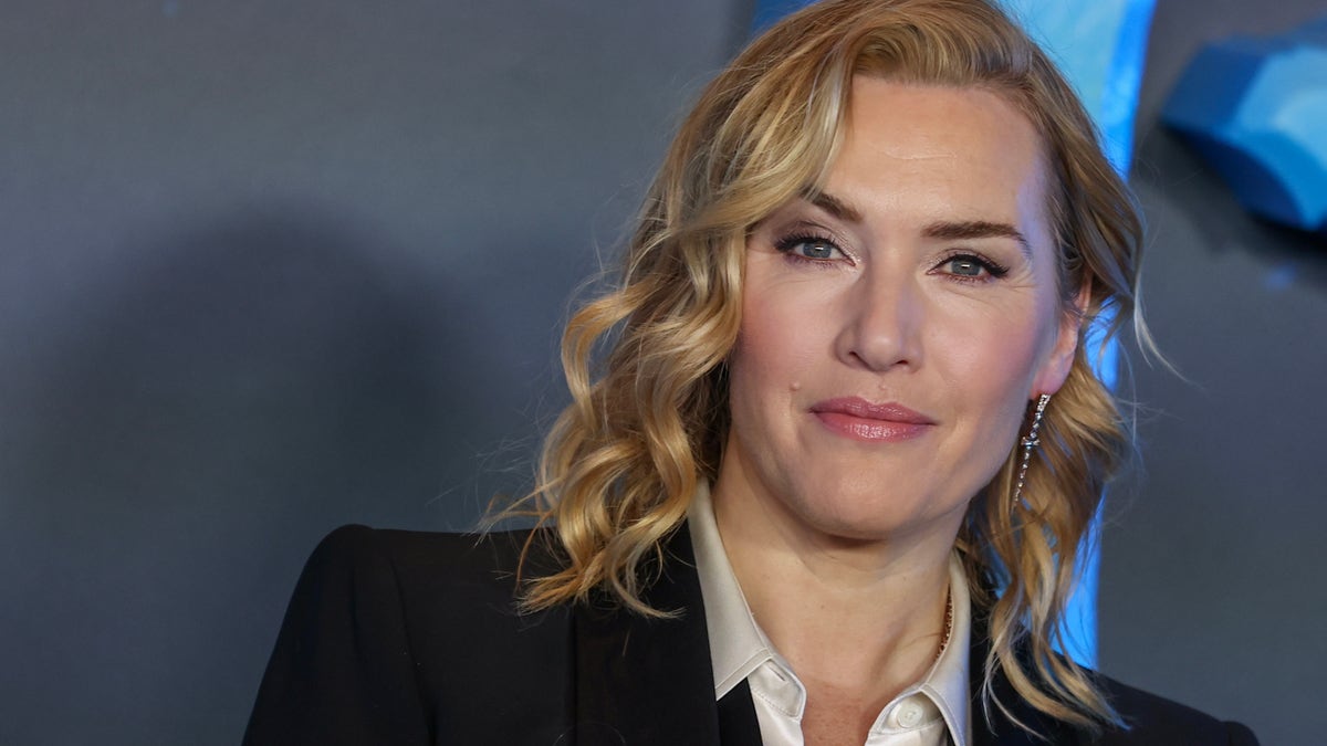 Kate Winslet with ringlet curls in a black suit and white top on red carpet