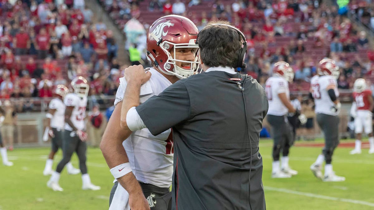 Gardner Minshew speaks with Mike Leach on the field in 2018