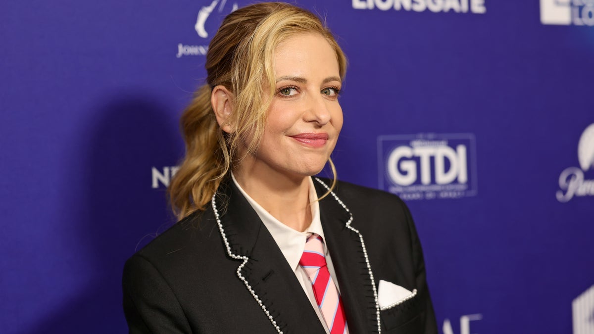 Sarah Michele Gellar with her hair in a ponytail, black blazer and red striped tie