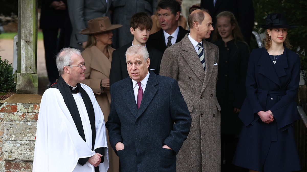 Prince Andrew in a blue coat and red tie was seen conversing with The Reverend Canon Dr. Paul Williams in a white robe