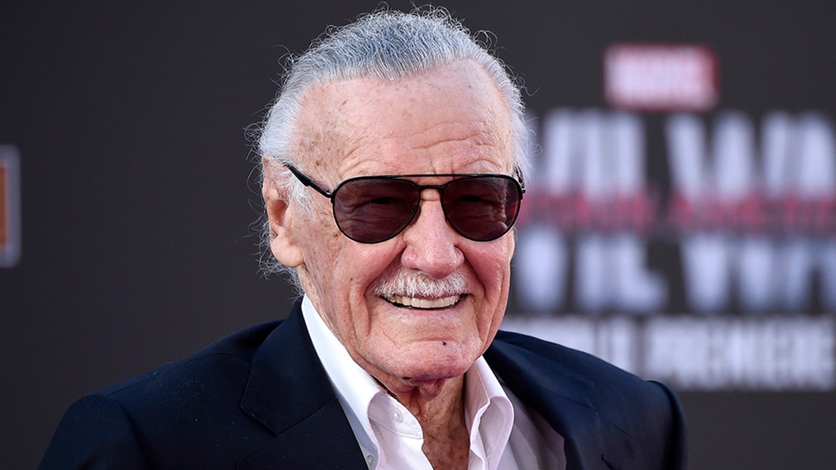 Stan Lee in a white button down suit and black sunglasses
